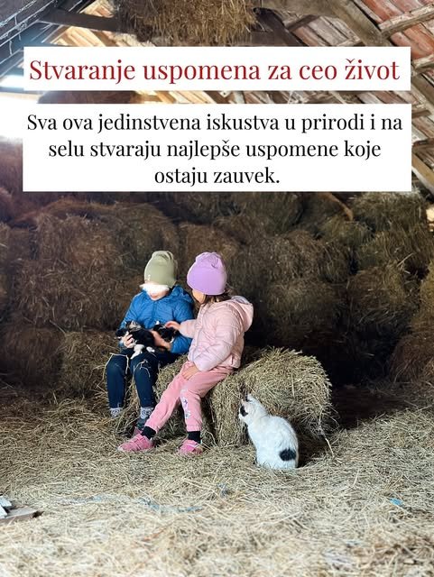 Dva deteta u kapama sede na balama slame u štali i maze male crne mačiće.