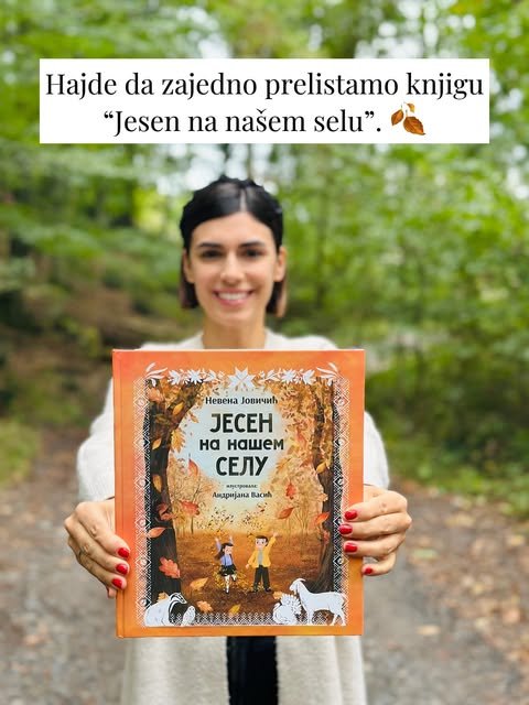Nevena Jovičić drži knjigu „Jesen na našem selu“ u jesenjoj šumi