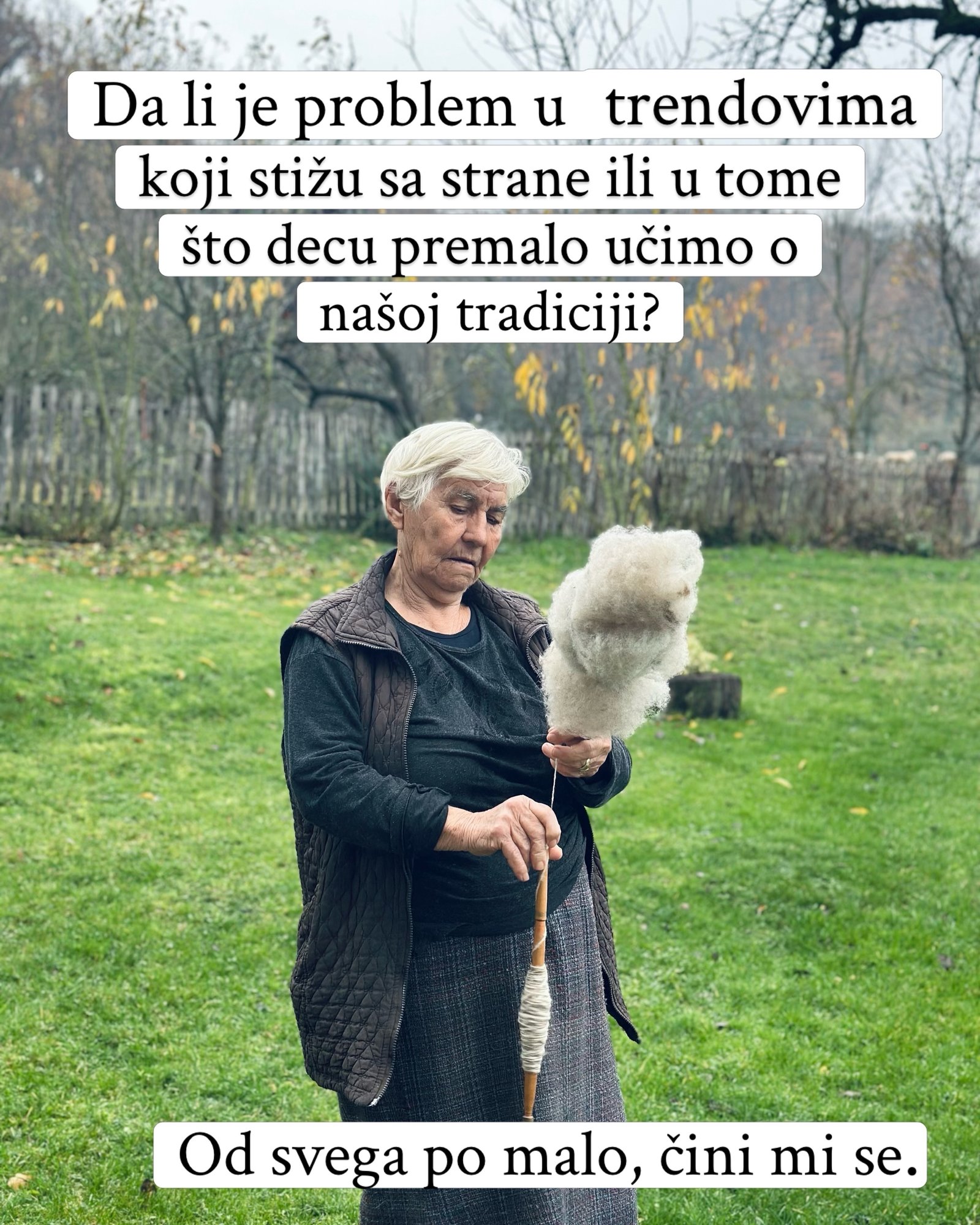 Baka u dvorištu prede belu vunu na drvenom vretenu.