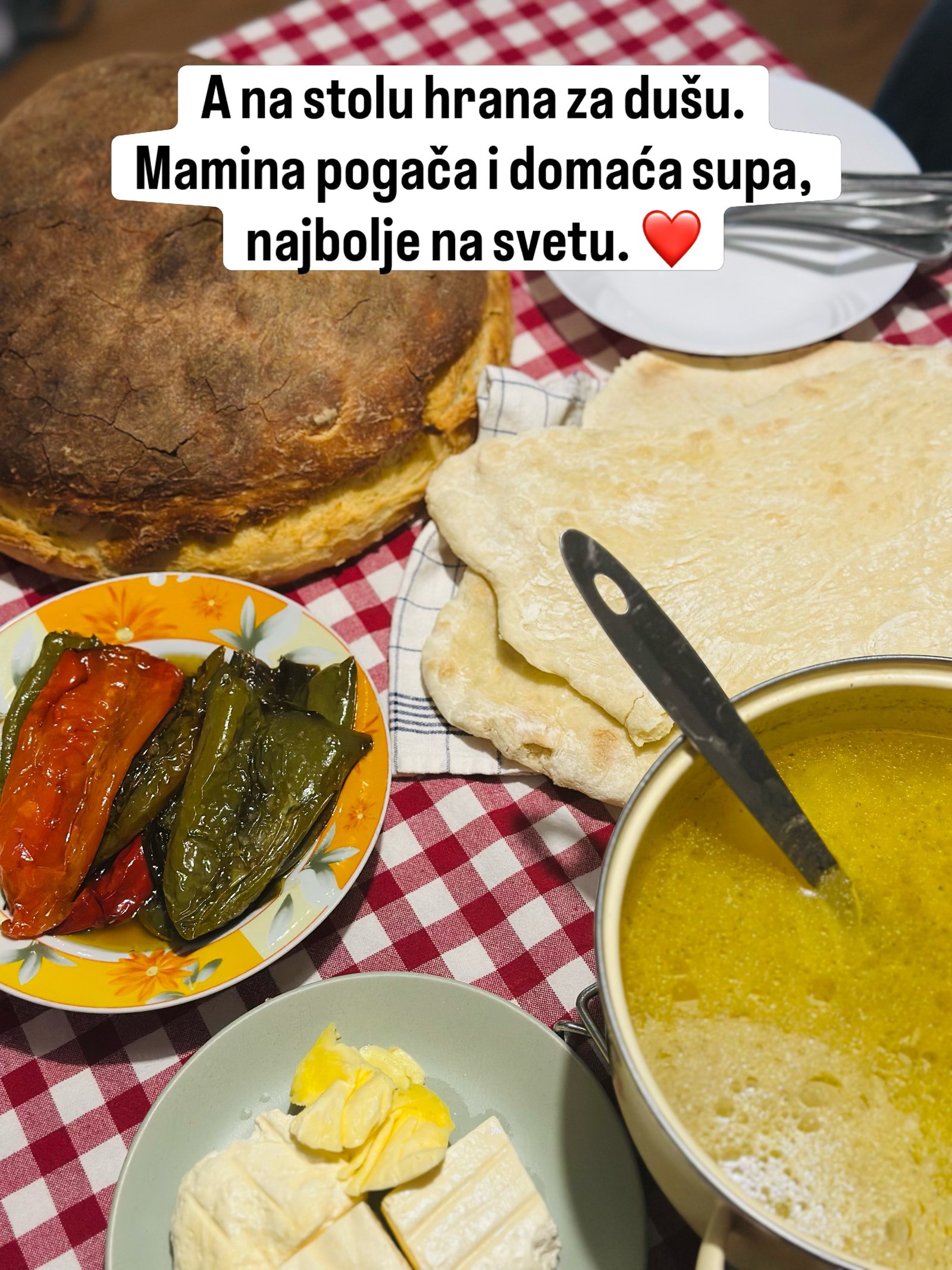 Sto sa kariranim stolnjakom, domaćom pogačom, supom, pečenim paprikama i sirom.
