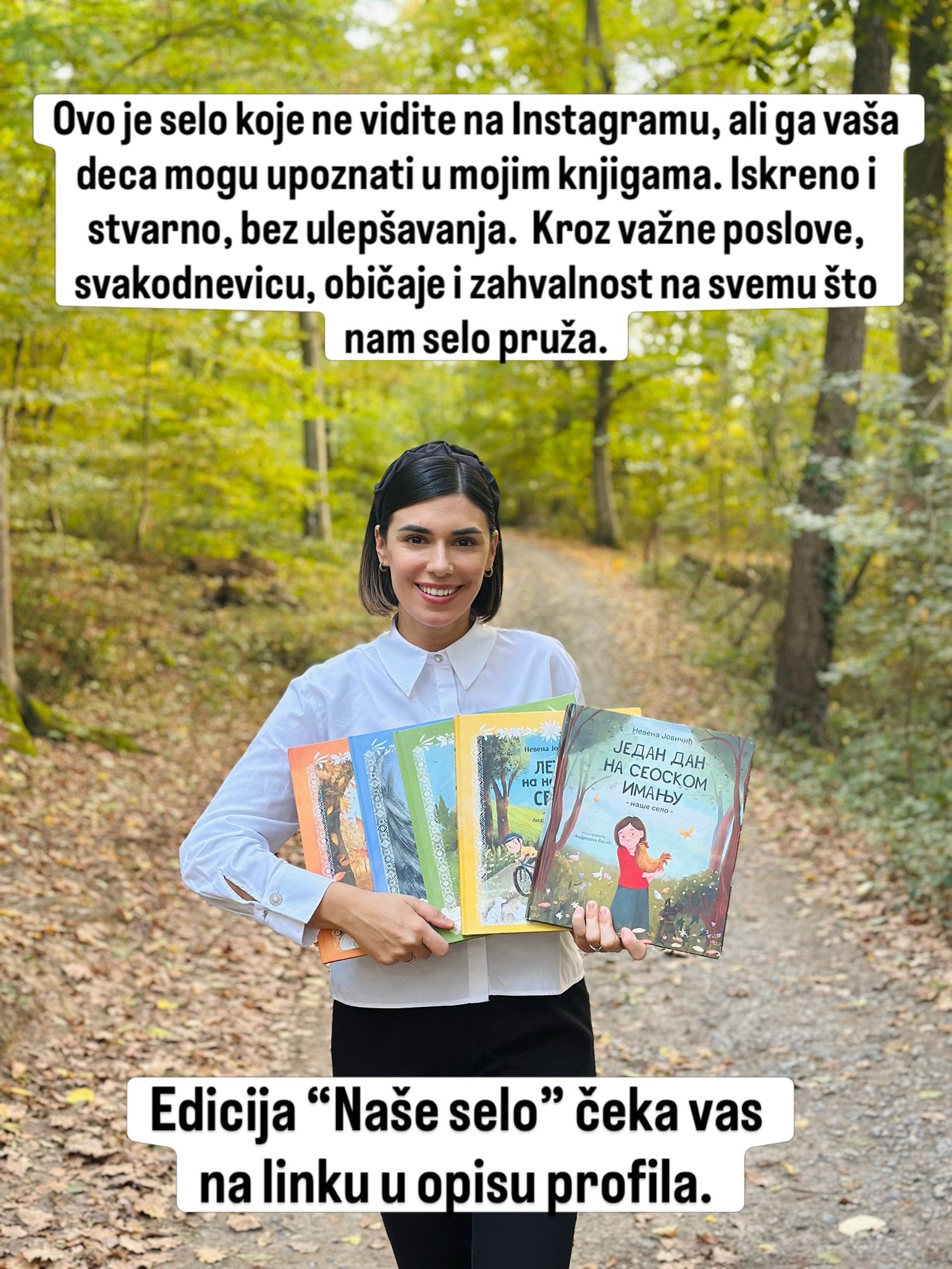 Nasmejana žena u beloj košulji drži pet knjiga na šumskoj stazi prekrivenoj jesenjim lišćem.