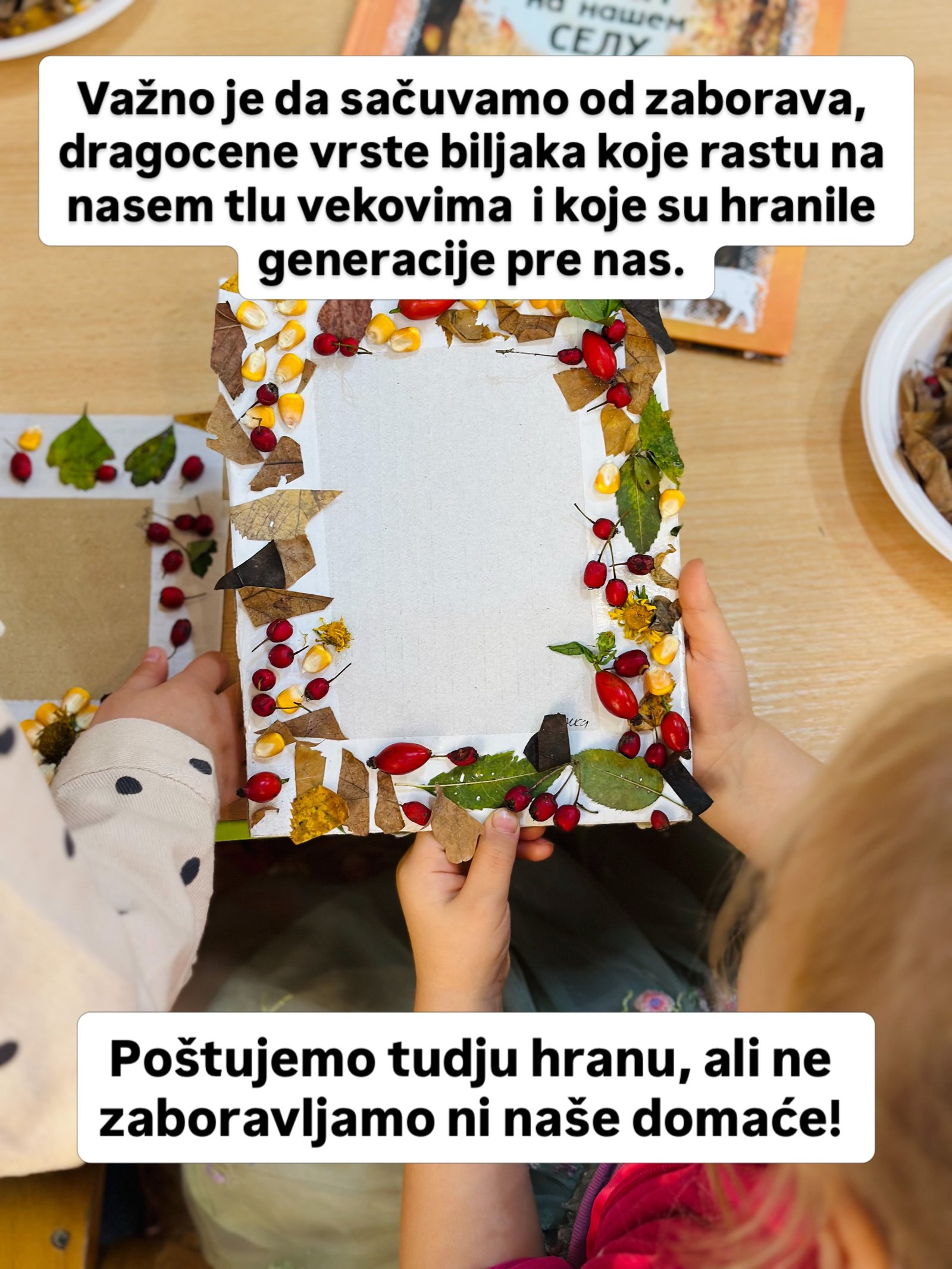 Dečje ruke drže kartonski okvir ukrašen suvim lišćem, zrnima kukuruza i crvenim bobicama